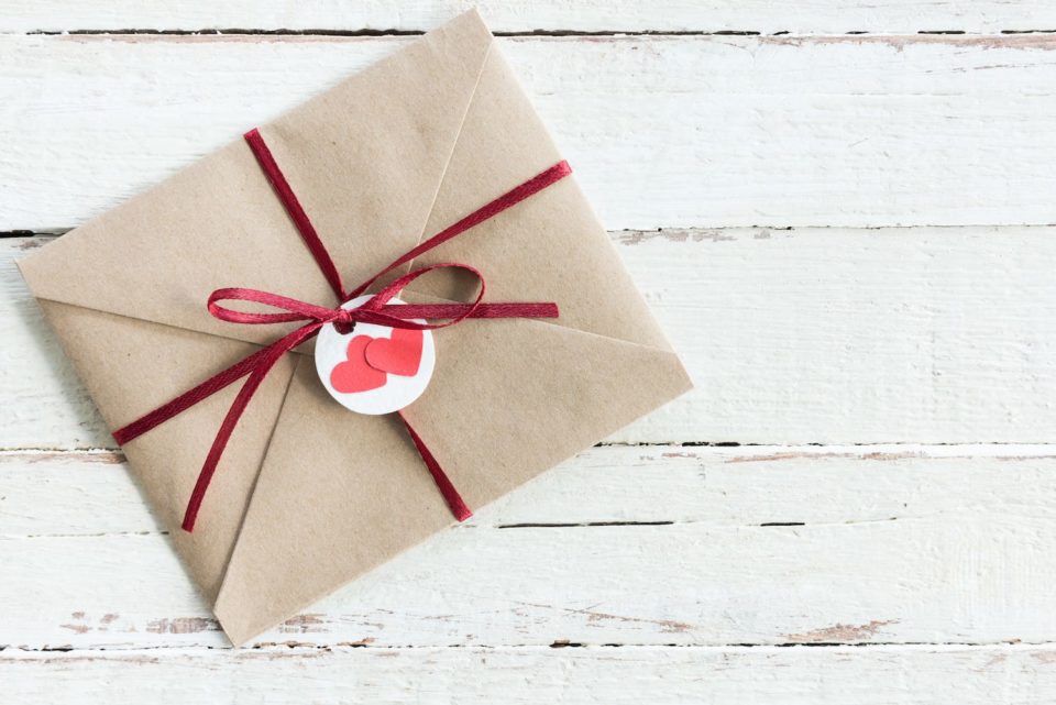 Geschenkideen zur Hochzeit - Brauner Umschlag mit rotem Schleifenband und zwei roten Herzen